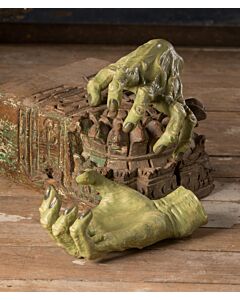 Pair of green witch hands with detailed wrinkles and long black fingernails, sculpted from paper pulp, positioned as if emerging from the ground, creating a spooky Halloween display.