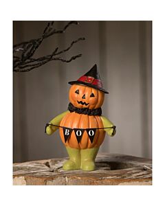 Figurine by Bethany Lowe featuring a small pumpkin head witch holding a 'BOO' banner, crafted from hand-painted resin, crepe paper, and paper. Ideal for decorating mantles or window sills with vintage-inspired Halloween charm.