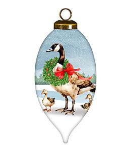 A graceful goose carries a festive wreath through a snowy landscape, accompanied by her playful goslings. This charming ornament captures the warmth and joy of family during the winter season.