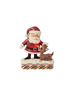 Santa tenderly pets Rudolph under the glow of Rudolph’s iconic shining nose, capturing a heartfelt moment of acceptance and love in this handcrafted Jim Shore design.
