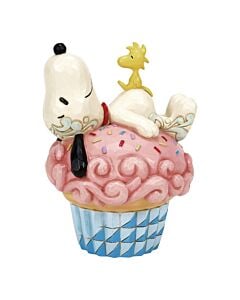Snoopy gently naps atop a decadent pink cupcake, lovingly decorated with swirling icing and sprinkles. Woodstock rests peacefully on Snoopy's back, while intricate rosemaling flourishes frame the festive scene in this Jim Shore collectible.