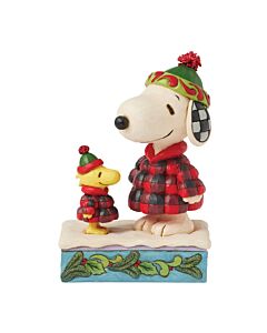 Jim Shore’s Cozy Companions figurine featuring Snoopy and Woodstock bundled in matching puffer jackets and knit hats, enjoying a snowy winter moment with heartwarming charm.