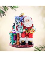 Santa Claus meticulously adds vibrant colors and highlights to his holiday masterpiece, showcasing his artistic flair. The 'Pretty as a Picture' ornament captures Santa’s dedication to creating festive beauty.
