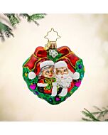 Mr. and Mrs. Claus share a sweet moment beneath the mistletoe, framed by a heart-shaped wreath. Their joyful expressions capture the warmth and romance of the holiday season.