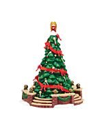 Festively decorated town Christmas tree standing tall with ornaments and lights, serving as the seasonal centerpiece of a Dickens’ Village scene.
