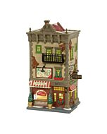 Charming corner pizzeria with weathered stucco, a classic Italian-style facade, and a front window displaying fresh pizza for takeout.