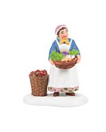 A cheerful shopkeeper stands beside baskets overflowing with colorful fruits and vegetables in a quaint village market setting.