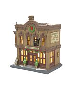 Classic brick furniture store adorned with seasonal décor, featuring visible shipments like headboards stacked at the side entrance.