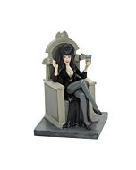 Elvira figure holding a movie reel and signing autographs, celebrating her big screen success in a playful Halloween village accessory.