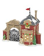 Brick entrance with ornate iron gates welcoming villagers into a festive Christmas market decorated for the season.