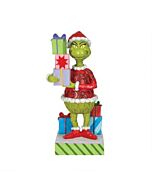 A colorful Jim Shore figurine features the Grinch with a mischievous grin, dressed in his classic red Santa suit, clutching a teetering stack of brightly wrapped Christmas presents, capturing that iconic moment of holiday mischief—whether he's stealing or
