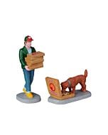 A pizza delivery man in a green jacket holds 5pizza boxes, while a happy dog feasts on another.